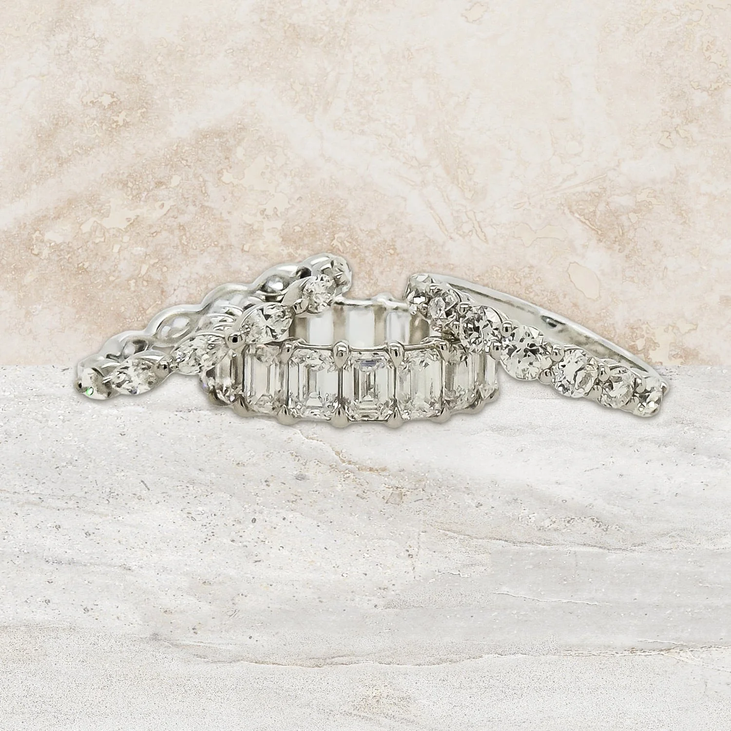 Three silver and diamond rings, including a diamond eternity band, displayed on a light textured surface with a marbled background.