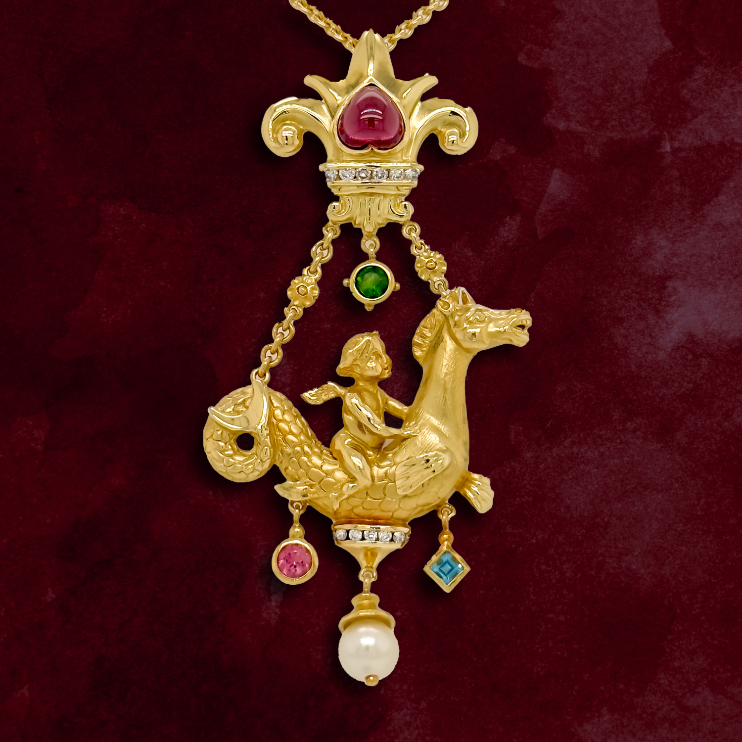 Gold pendant with colorful gemstones featuring a cherub riding a seahorse, suspended from a gold chain, against a red background.