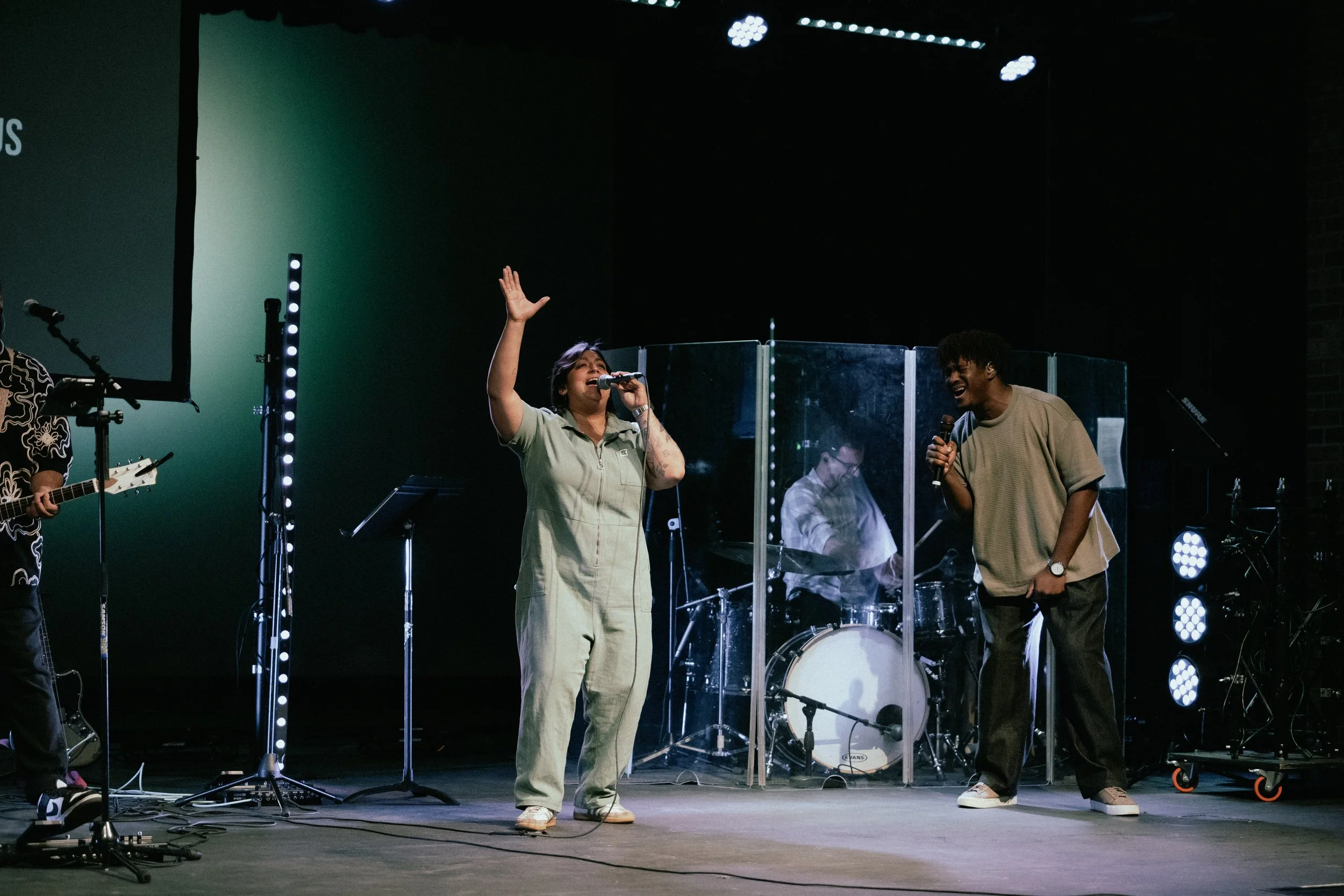 vocalists and guitar player leading worship on stage