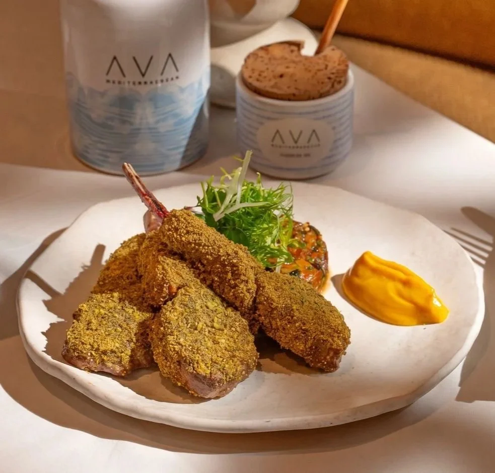 Plated breaded meat croquettes with herbs, vegetables, and orange dipping sauce at a restaurant table