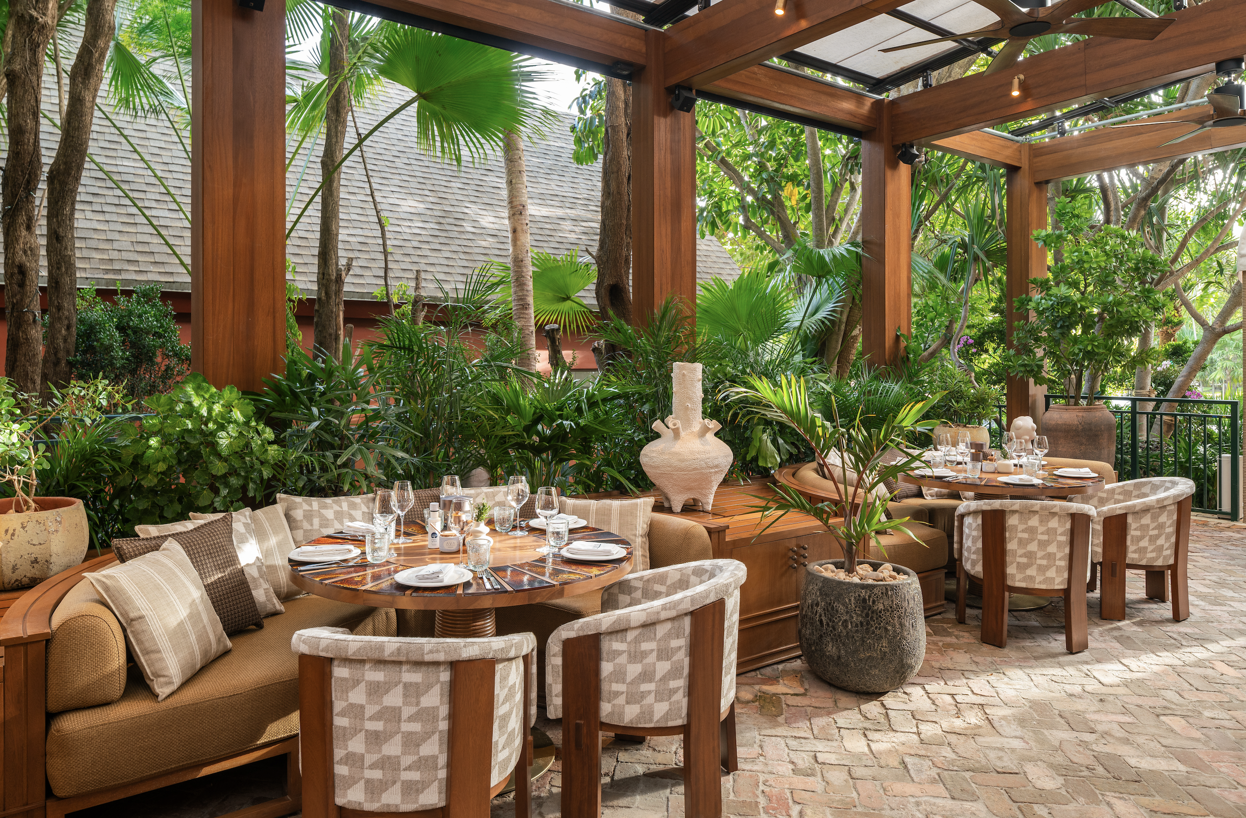 AVA Coconut Grove's outdoor dining area, with round half booths near plants.