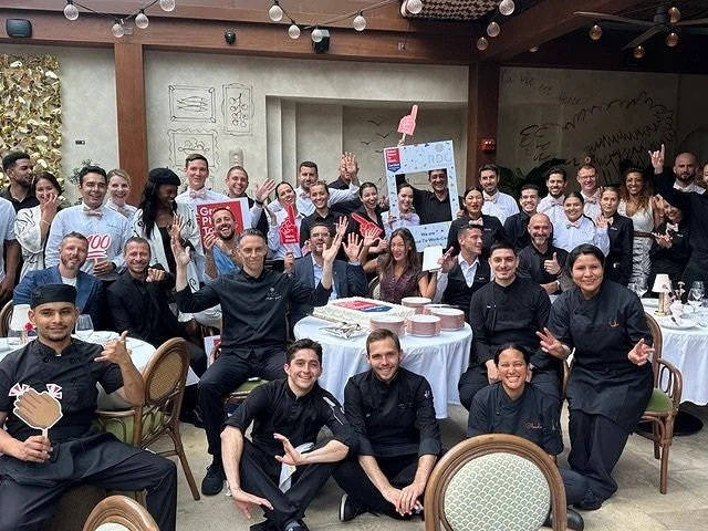 Riviera Dining Group employees celebrating getting the cerification of a "Great Place to Work", with a celebration cake.