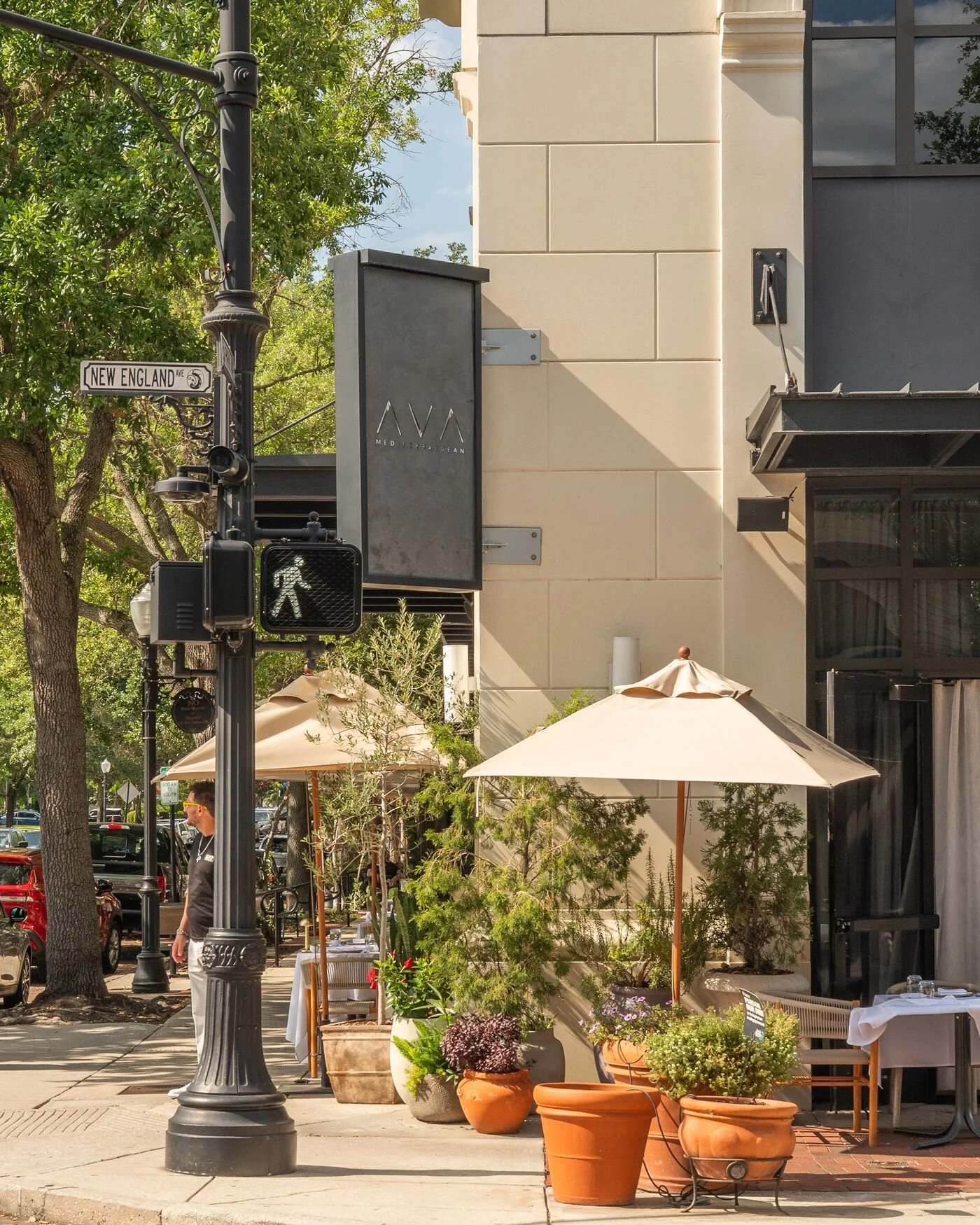 Outdoor restaurant patio with umbrellas and potted plants on New England Avenue