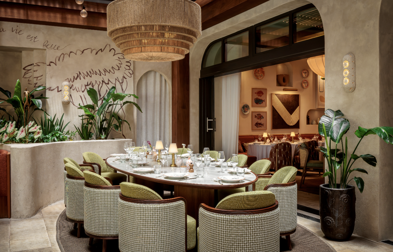 Dining table setting at CLAUDIE with green chairs in an elegant setting.