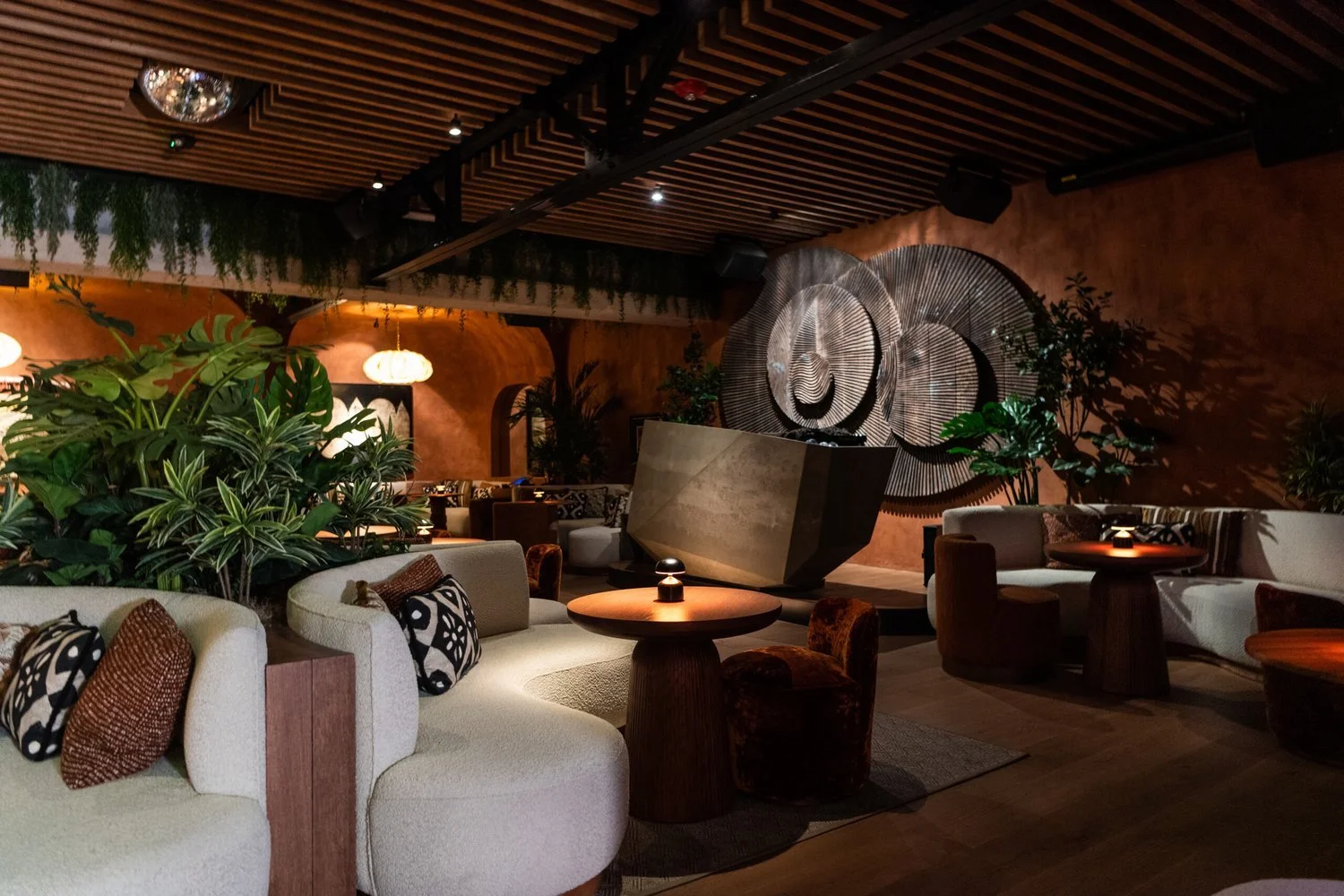 The MILA Lounge with African-inspired decoration, including unique artwork on the walls, greenery next to the couches and tables, and a silver disco ball for dancing.