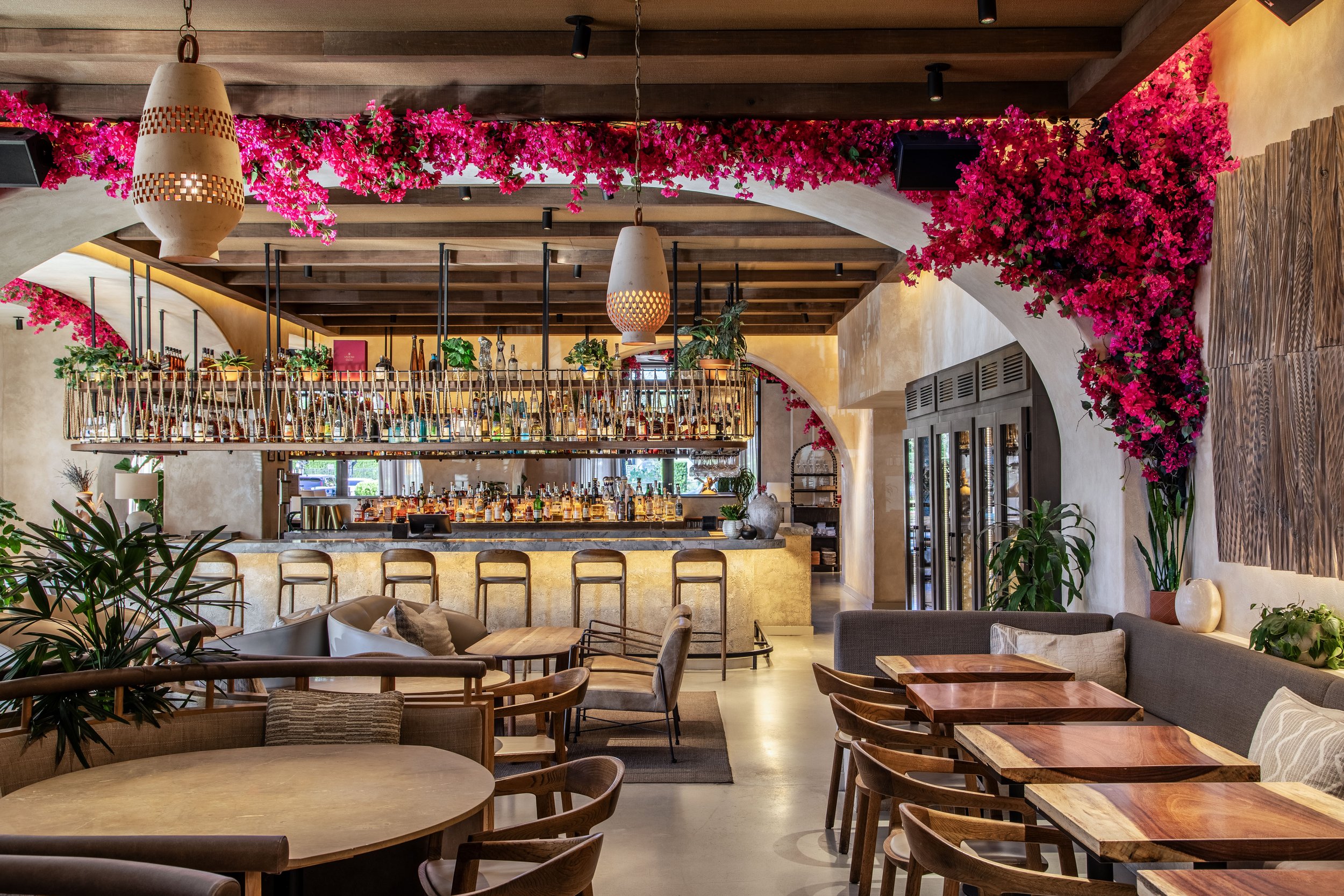 AVA Winter Park's dining area with pink flowers on the walls and ceiling, with a bar in the background.