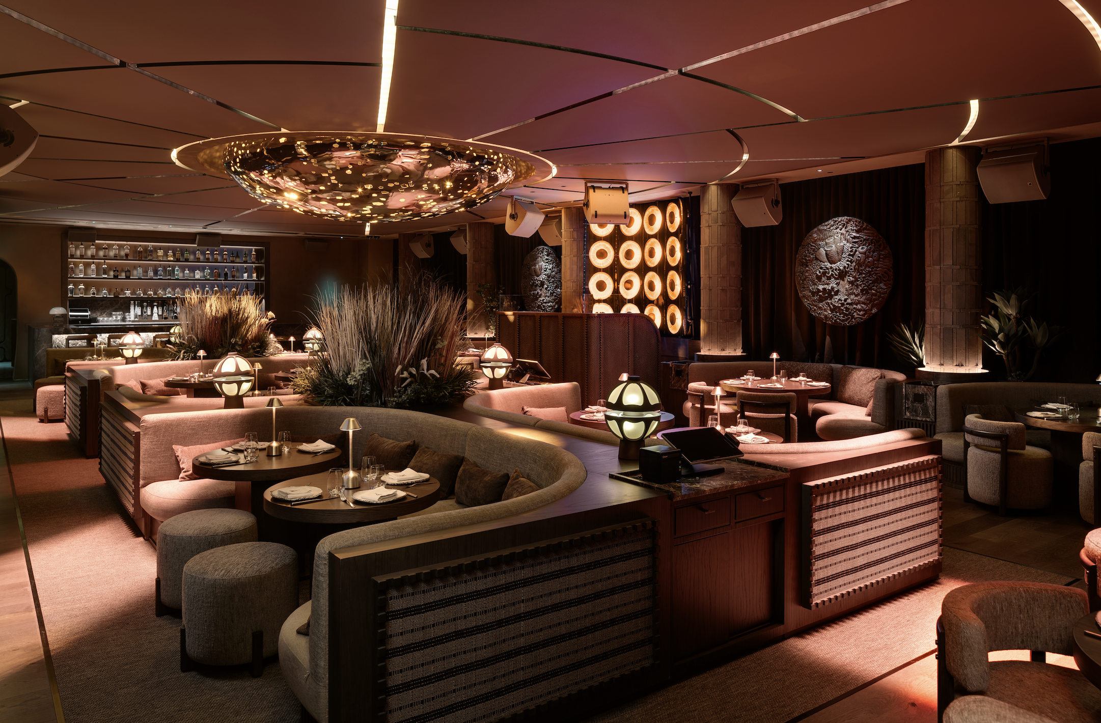 The luxurious lounge at CASA NEOS, with an elegant ambiance, dimmed lighting and unique decoration such as artwork on the walls, and a disco-like light.