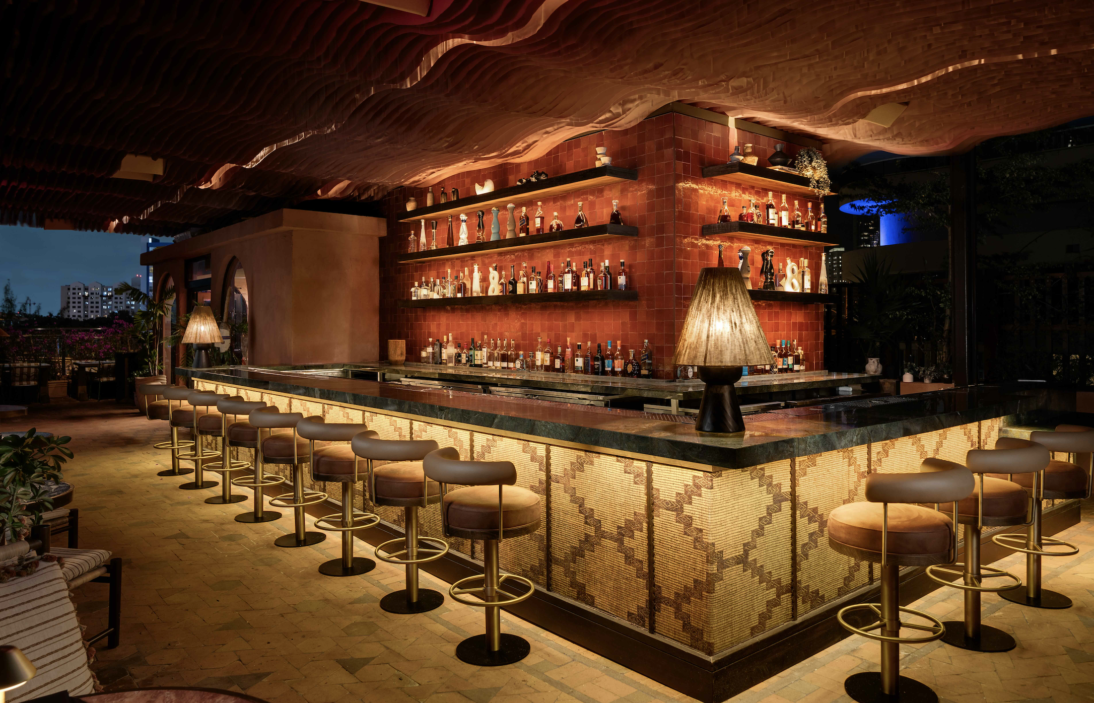 An outdoor rooftop bar for members-only at CASA NEOS, with an dimmed and elegant ambiance of a bar with barstools.