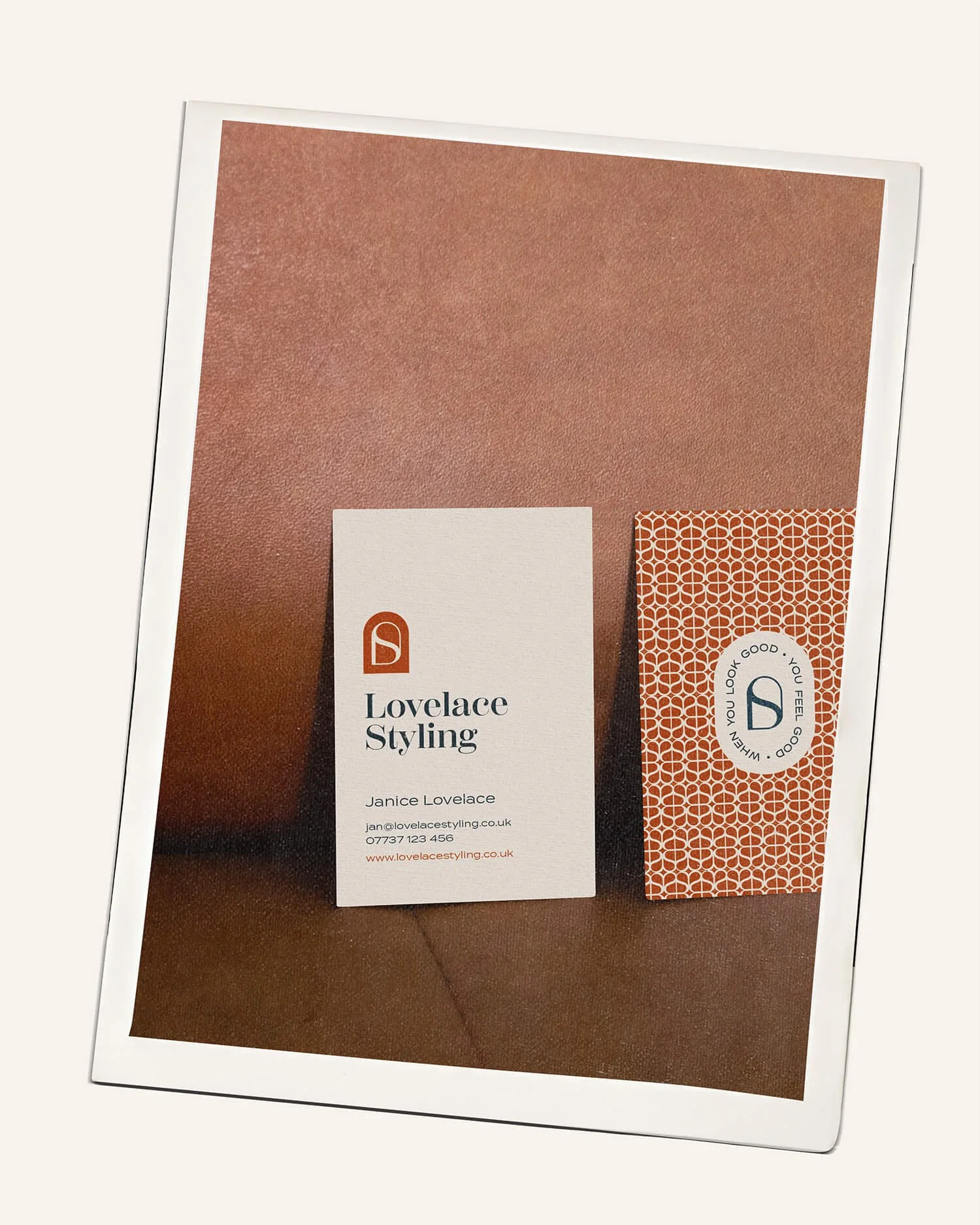 Business card and a patterned tag for Lovelace Styling on a brown textured surface.