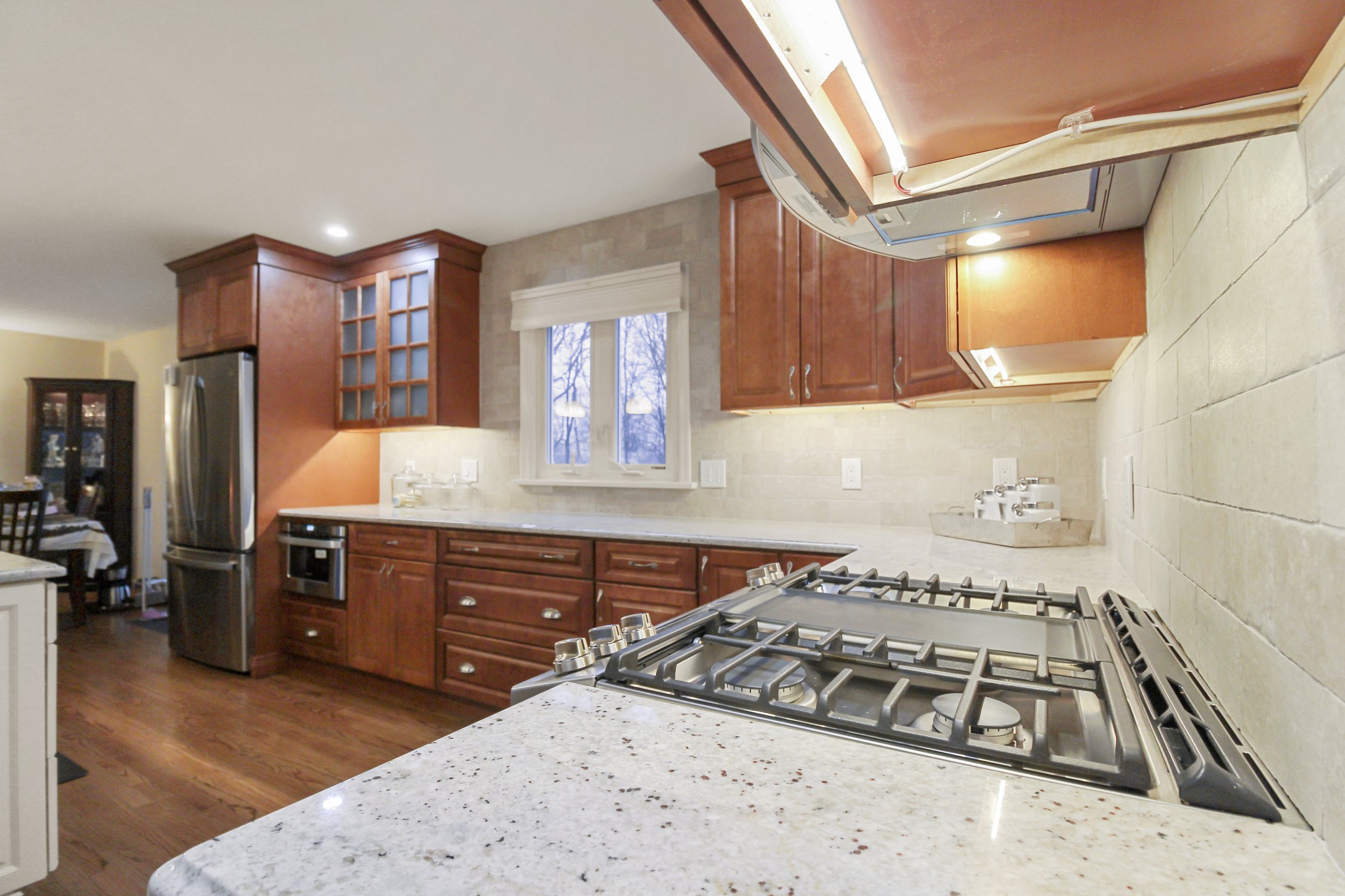Modern kitchen with wooden cabinets, stainless steel appliances, gas stove, and granite countertops.