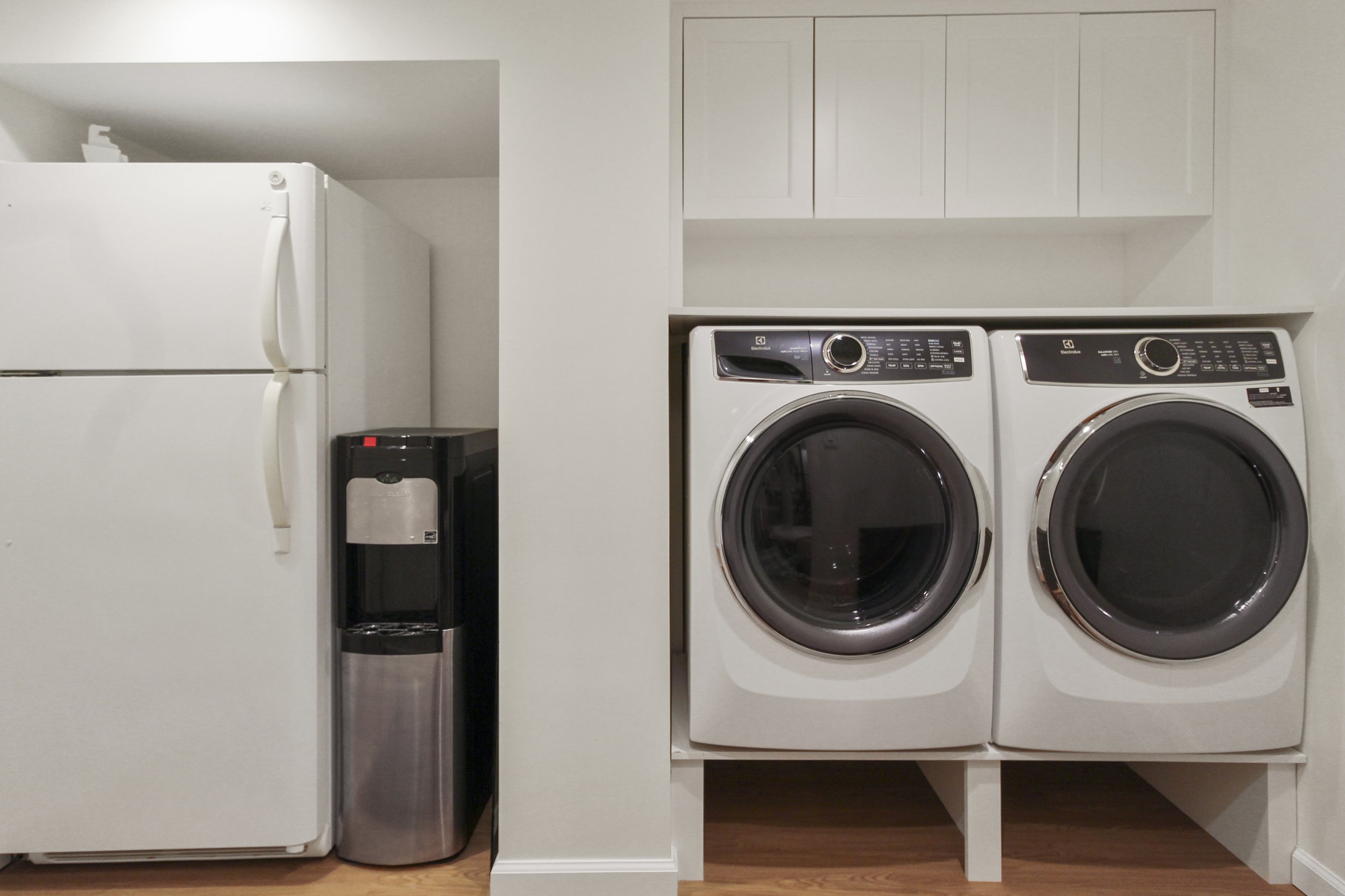 Laundry room with a refrigerator, water cooler, washer, and dryer