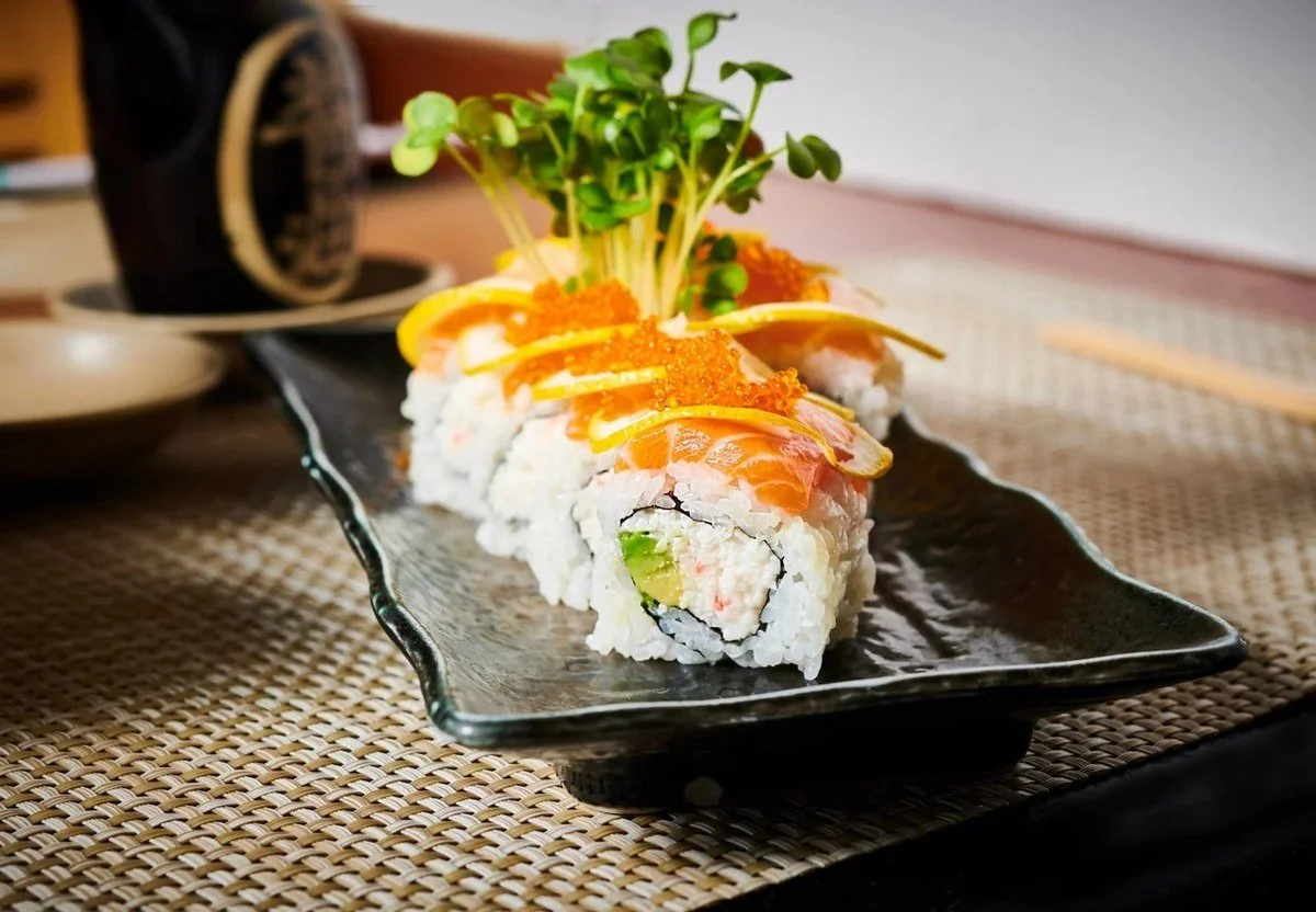 Sushi roll with microgreens on a black plate