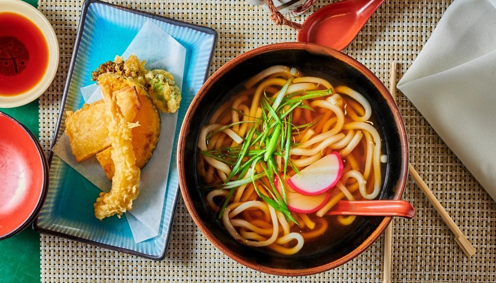 Udon noodle bowl with tempura on a colorful table. Asian food and restaurant photography.