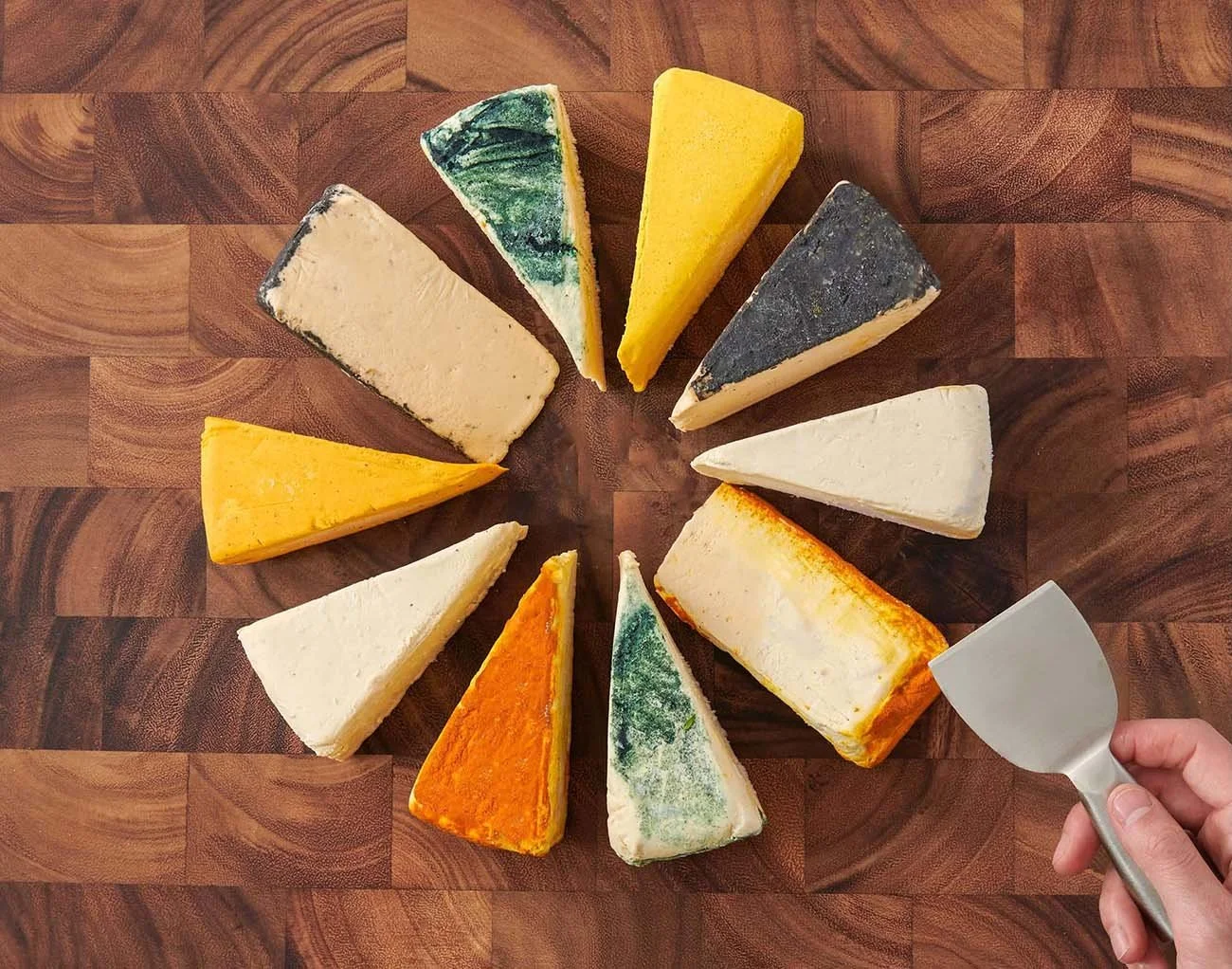 cpg beauty image vegan cheese wedges in wheel on board with hand lifestyle photo