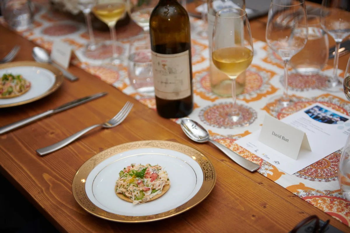Plated dish on a wooden table beside a glass of wine