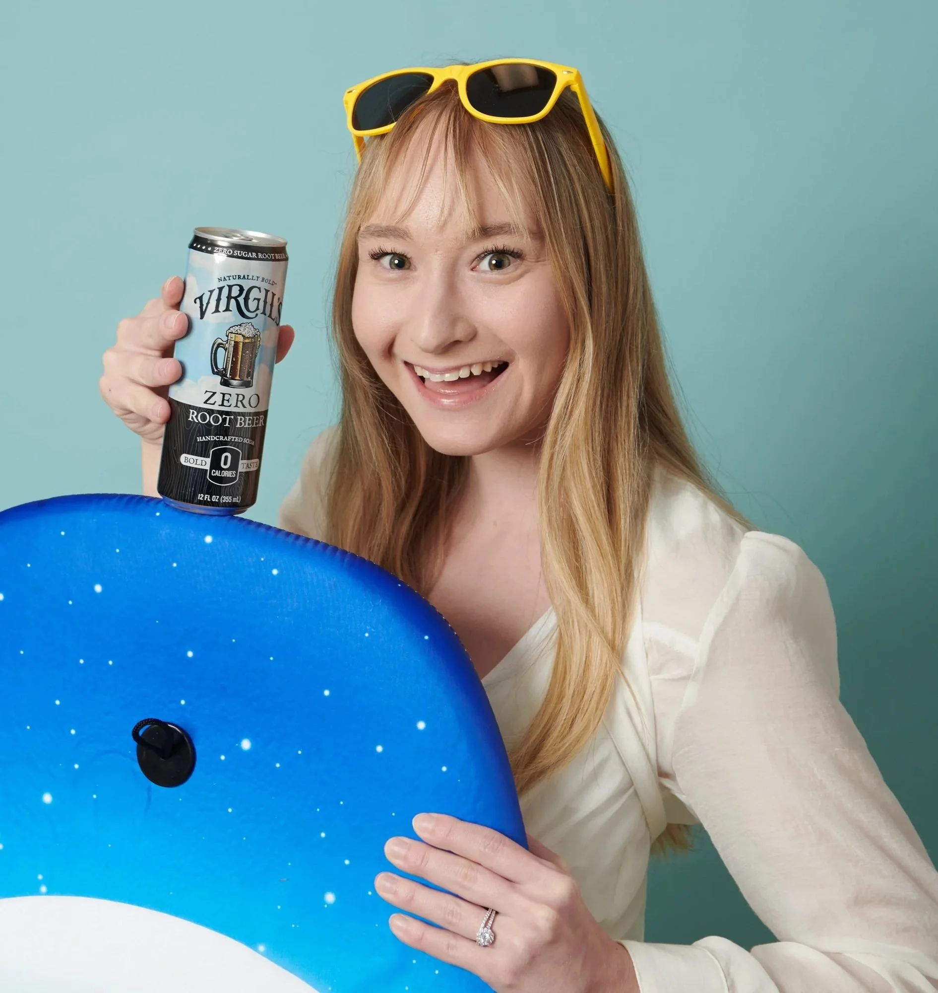 Smiling model holding a Virgil's Zero Sugar can with a blue pool float, CPG lifestyle photography
