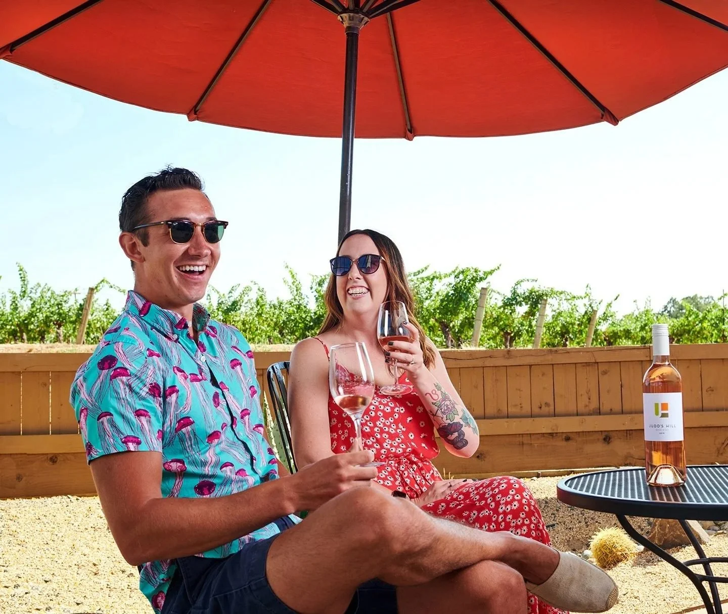 Couple relaxing under a red patio umbrella with drinks, lifestyle photography