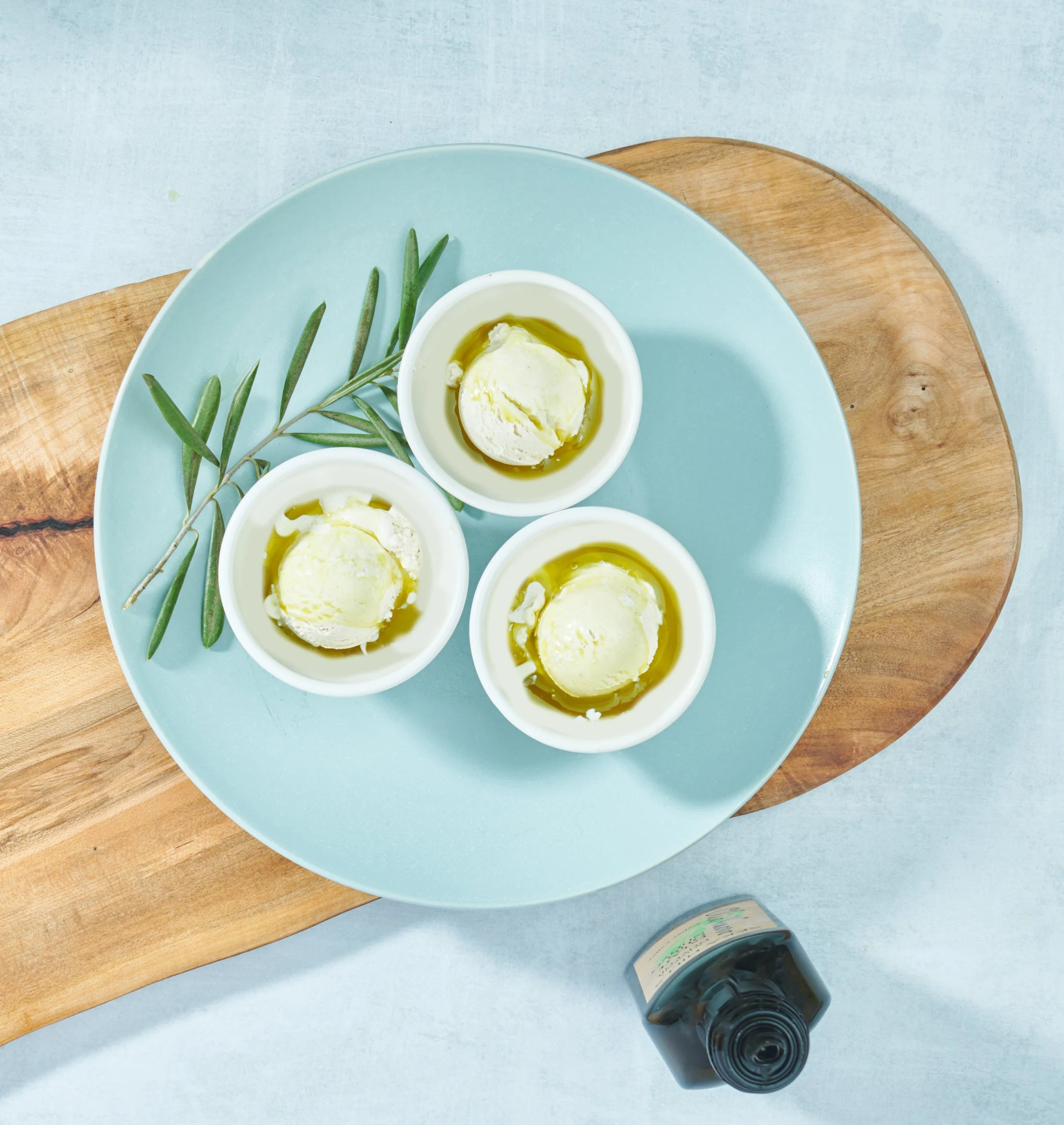 Olive oil ice cream with olio nuovo on a blue plate with rosemary