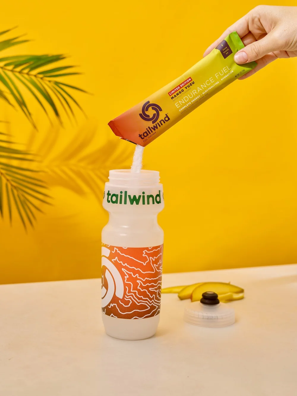 Hand holding a Tailwind drink mix stick on yellow, supplement photography