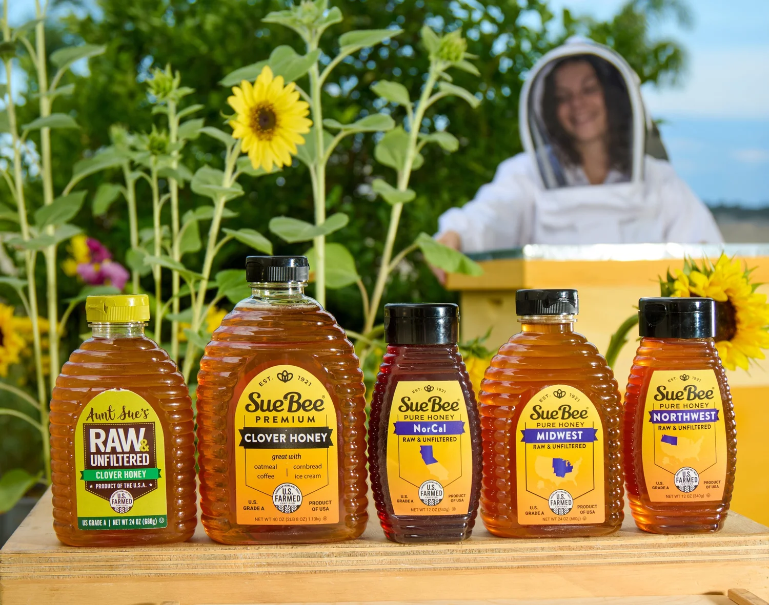 Honey lineup on a painted beehive with a beekeeper and sunflowers