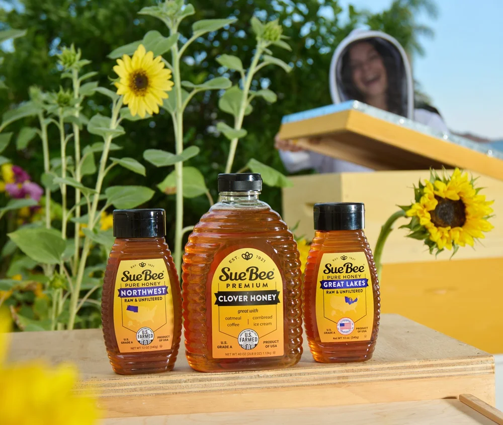 Honey bottles in front of sunflowers and a beekeeper