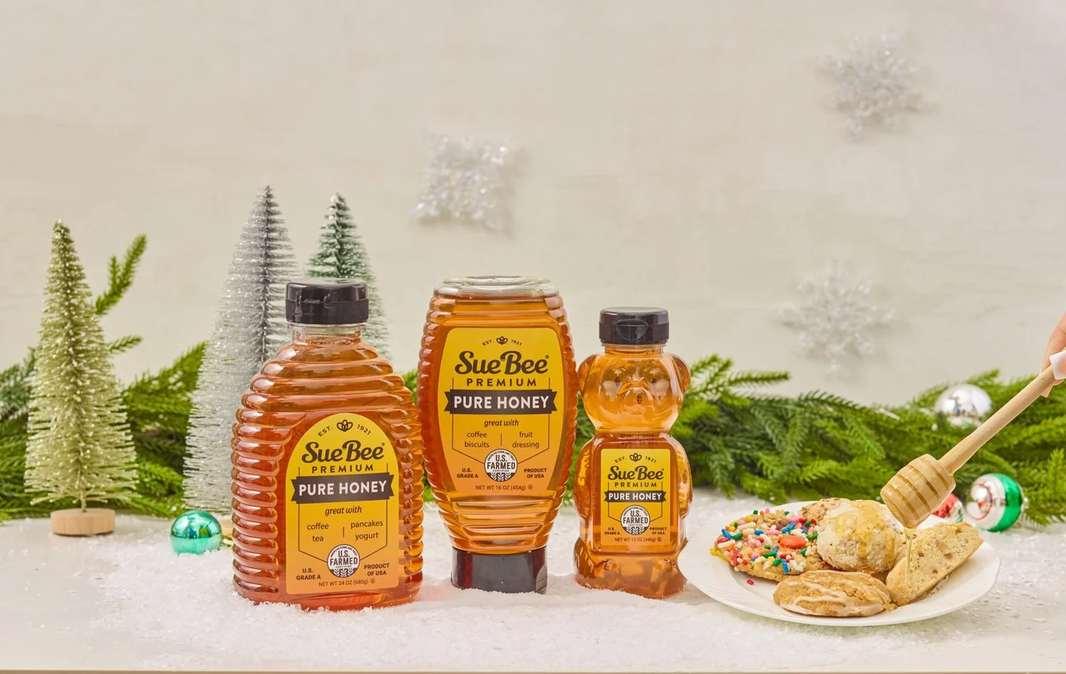 Honey product lineup on a snowy Christmas set with mini trees