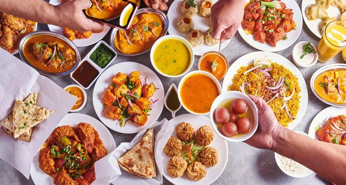 Indian restaurant table spread with hands sharing dishes
