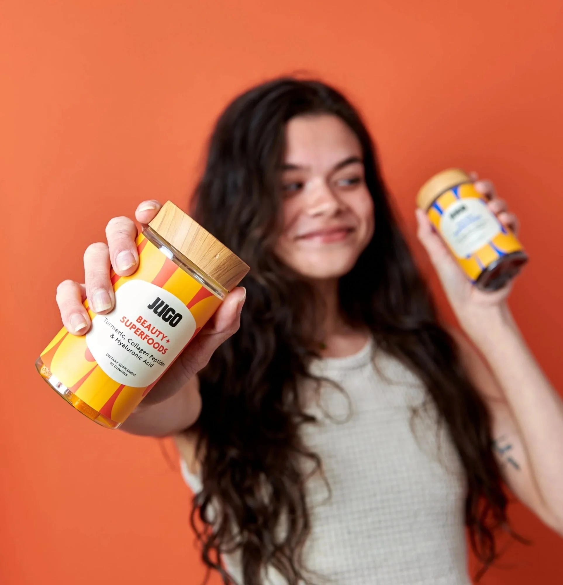 Model holding two snack jars on orange, CPG lifestyle photography