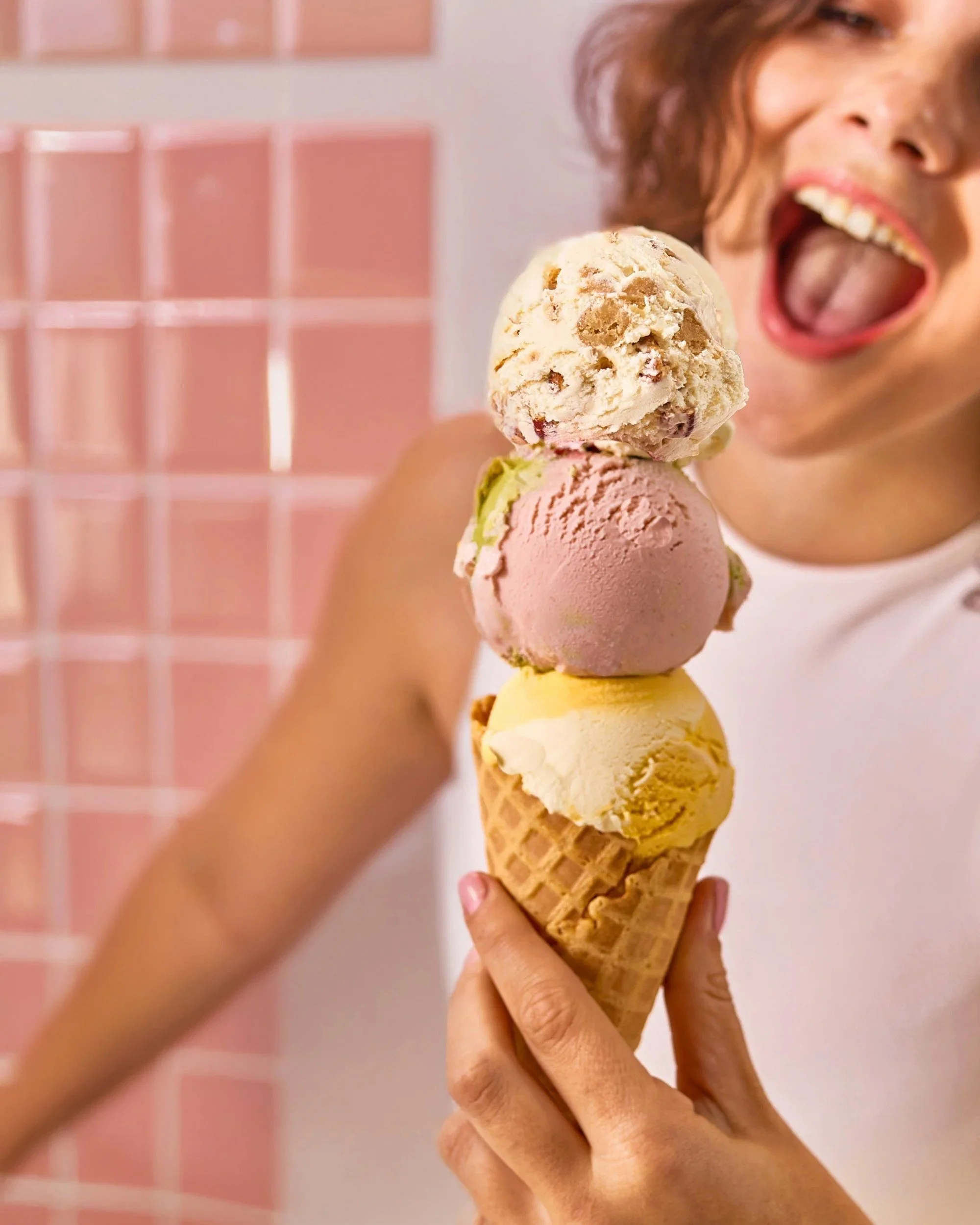 Woman with a triple-scoop ice cream cone in a pink kitchen, lifestyle food photography