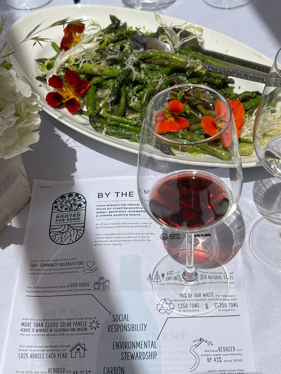 Asparagus salad with edible flowers beside a glass of red wine