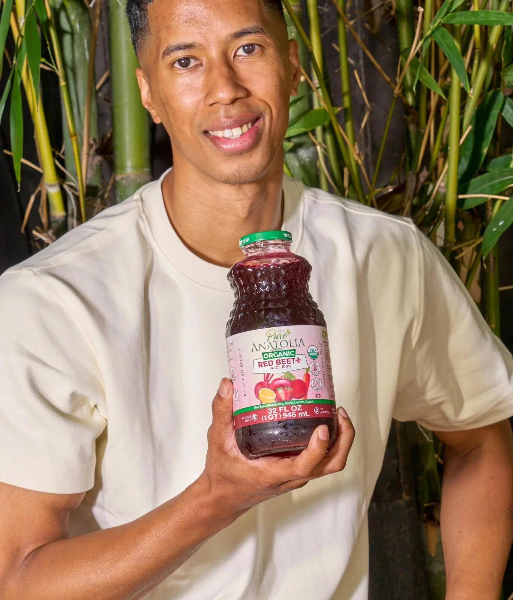 Smiling man holding a Pure Anatolia juice bottle in a bamboo garden, CPG lifestyle photography
