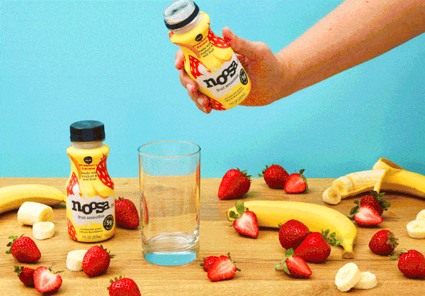 Noosa fruit smoothie poured into a glass with strawberries and bananas on blue stop motion GIF, CPG beverage video