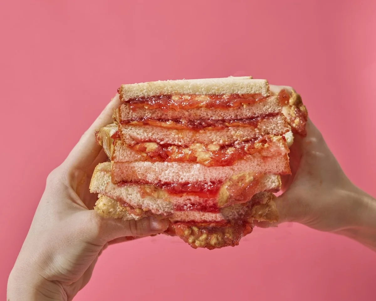 peanut butter and jelly whopper sandwich food photo bright pink messy modern with hands