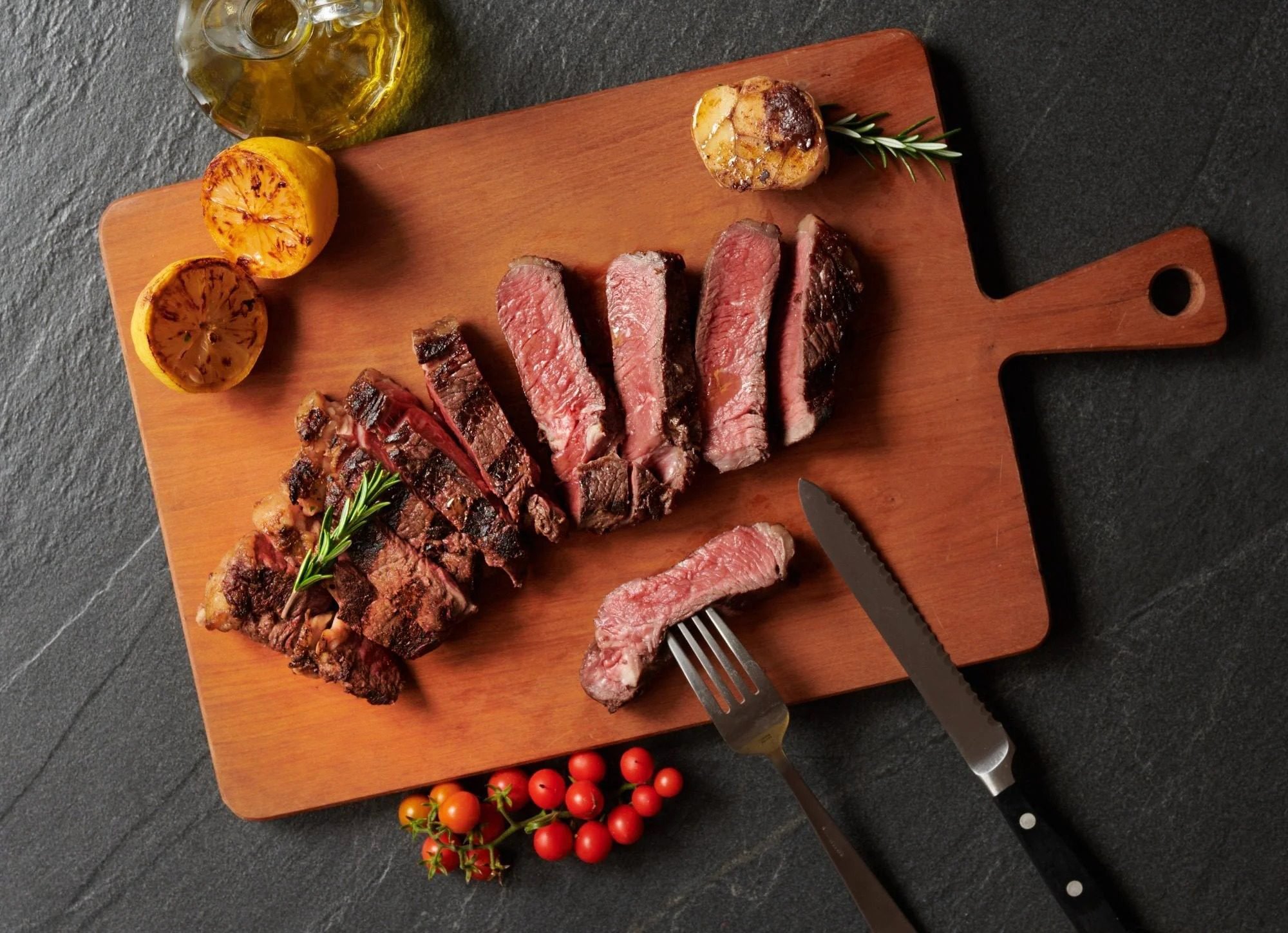 Sliced sirloin steak on a cutting board with a knife. Meat photography for butchers, grocers and meat brands.