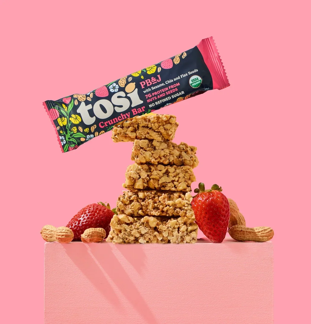 Tosi bar on a stack of snack bites with strawberries on pink, CPG photography