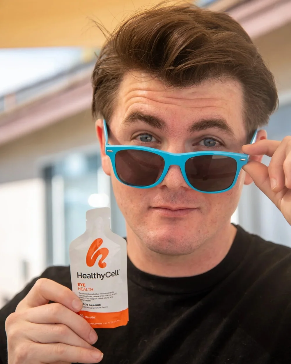 Man in blue sunglasses holding a Healthy Cell supplement pouch, CPG lifestyle photography