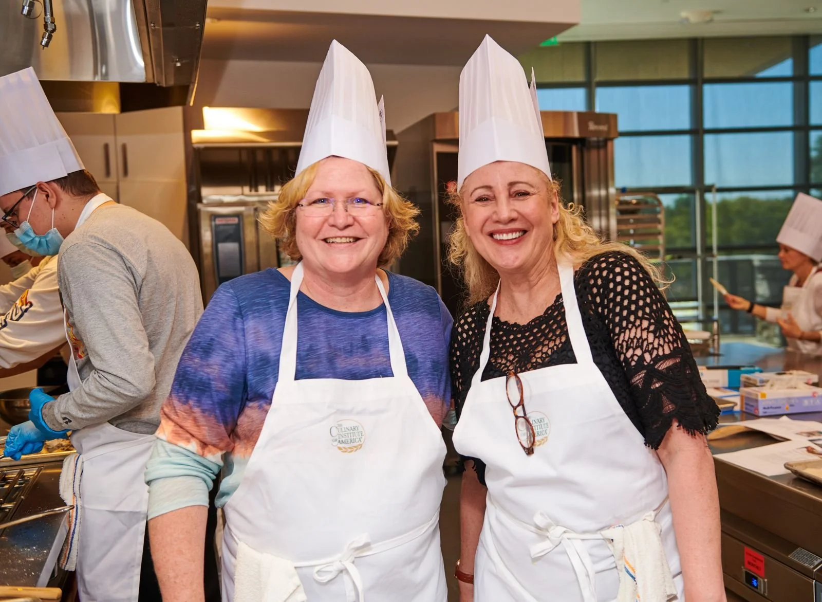 Two smiling cooking class chefs in toques at the CIA