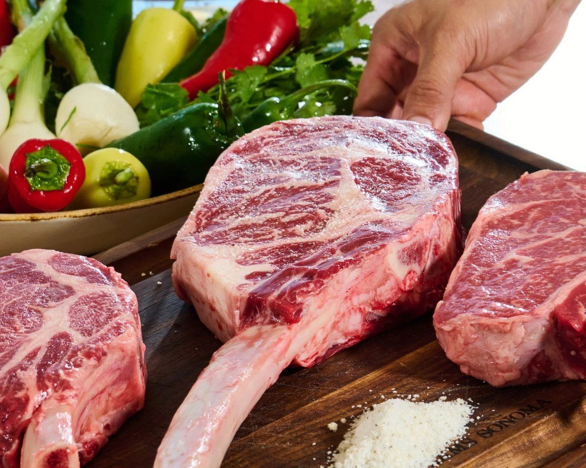 Raw ribeye steak presented with fresh peppers