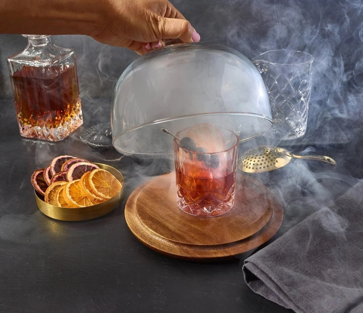 Smoked cocktail revealed from a glass cloche with citrus garnish, restaurant beverage photography
