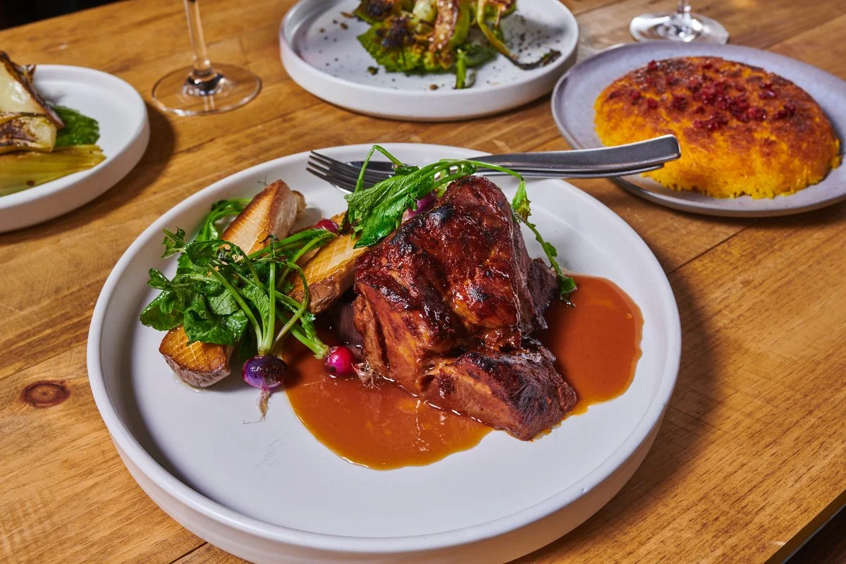 Braised meat with greens and gravy on a white plate