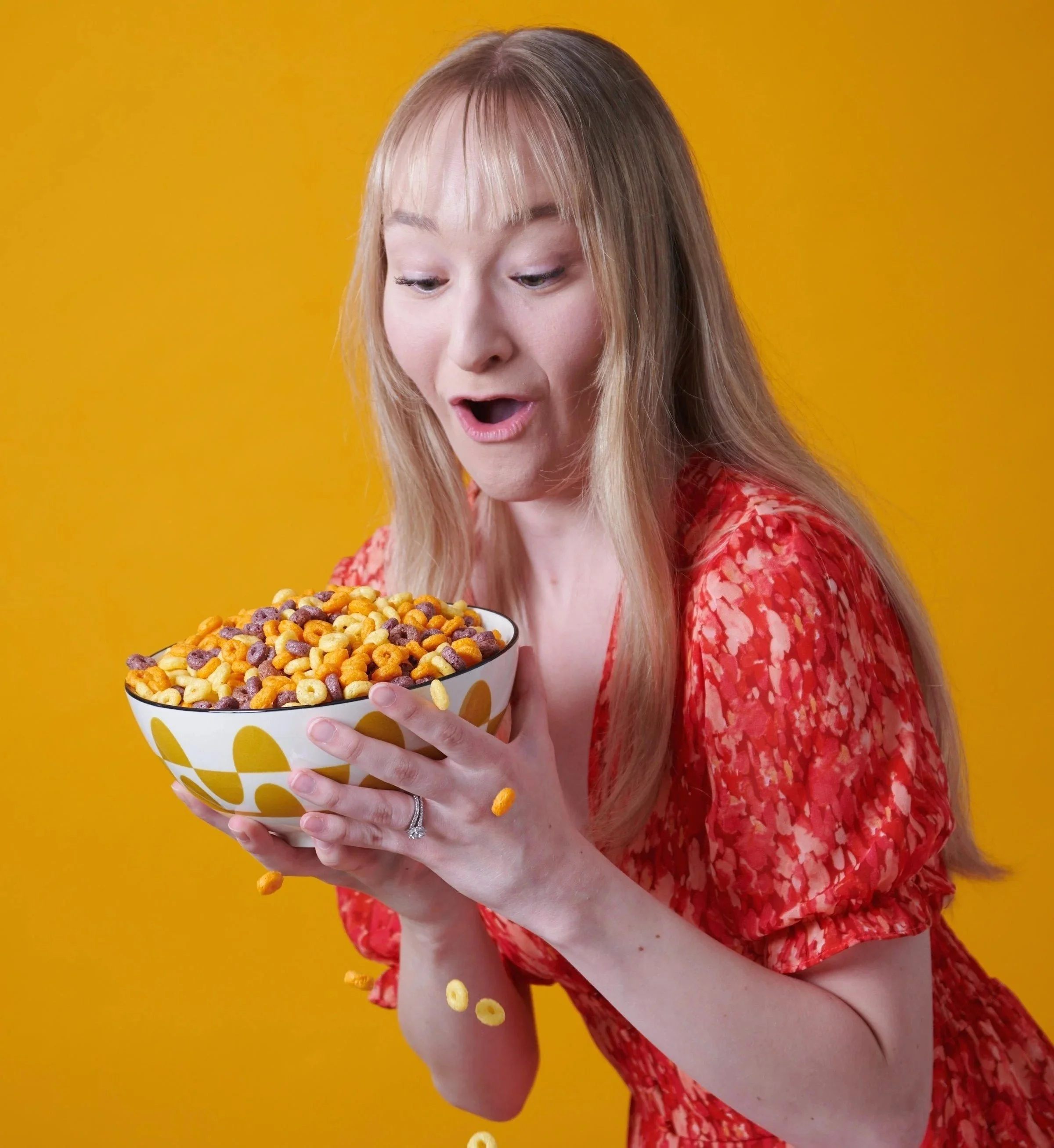 Surprised woman holding a bowl of popcorn on yellow, lifestyle CPG photography