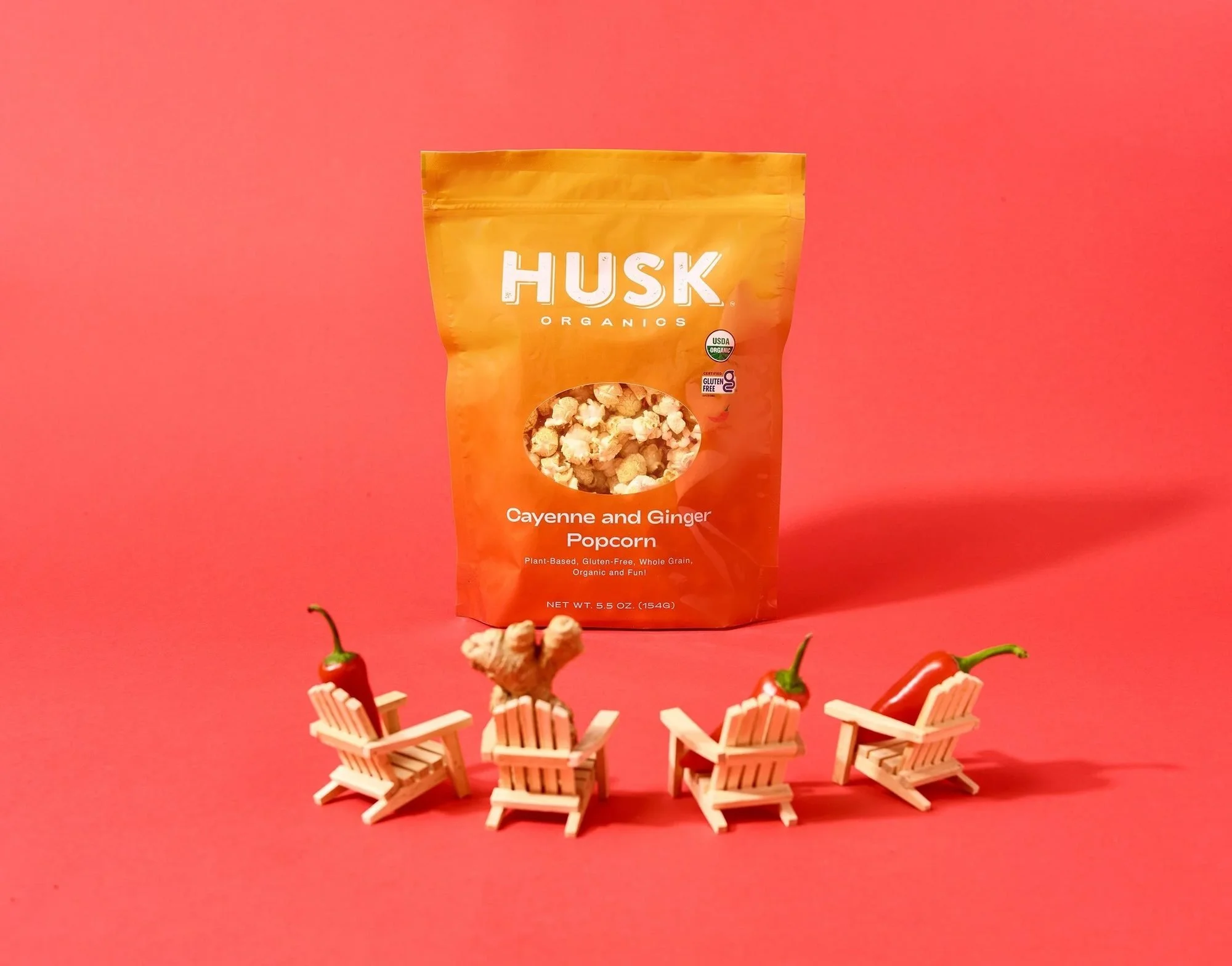 Husk Organics popcorn bag with mini beach chairs on red, creative CPG photography