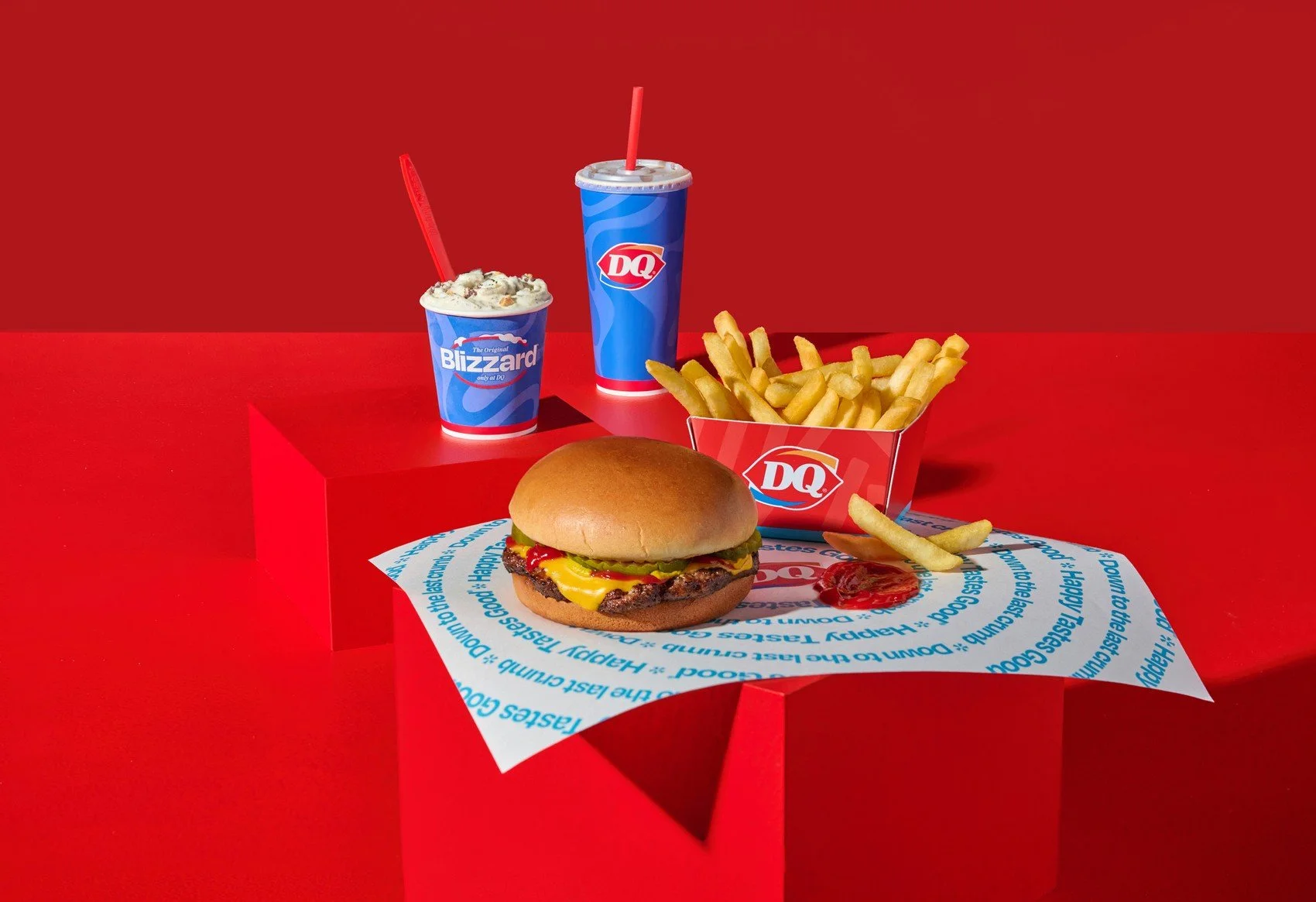 Dairy Queen burger meal with fries and Blizzard treats on a red set. Quick-service restaurant photography for national brands.