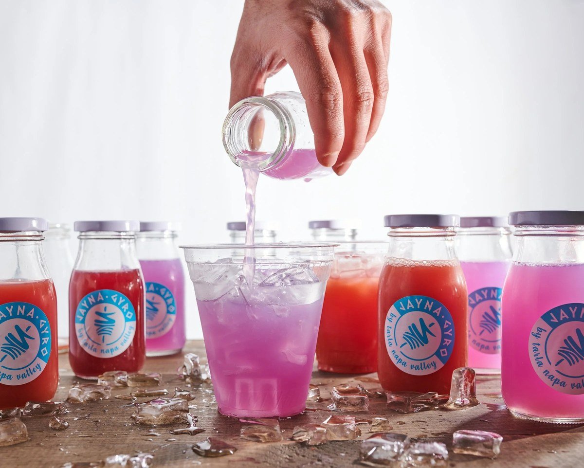 Pouring a purple drink beside bottled beverages