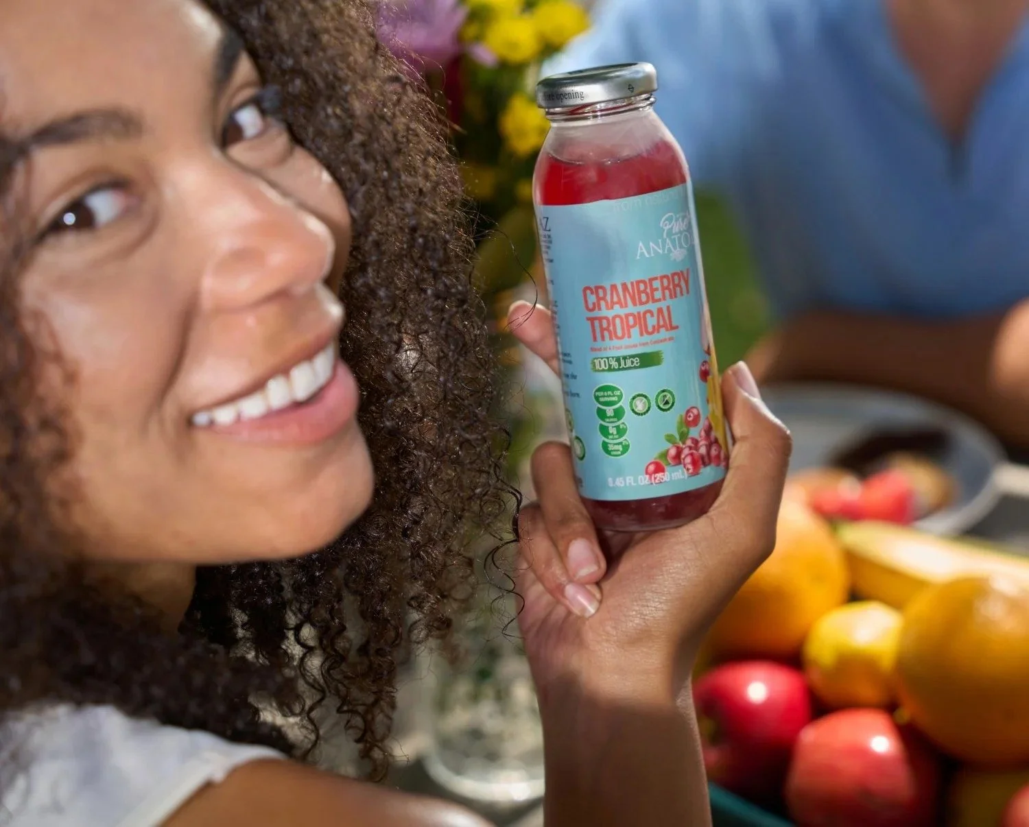 Smiling woman holding a juice bottle with fruit, lifestyle beverage photography