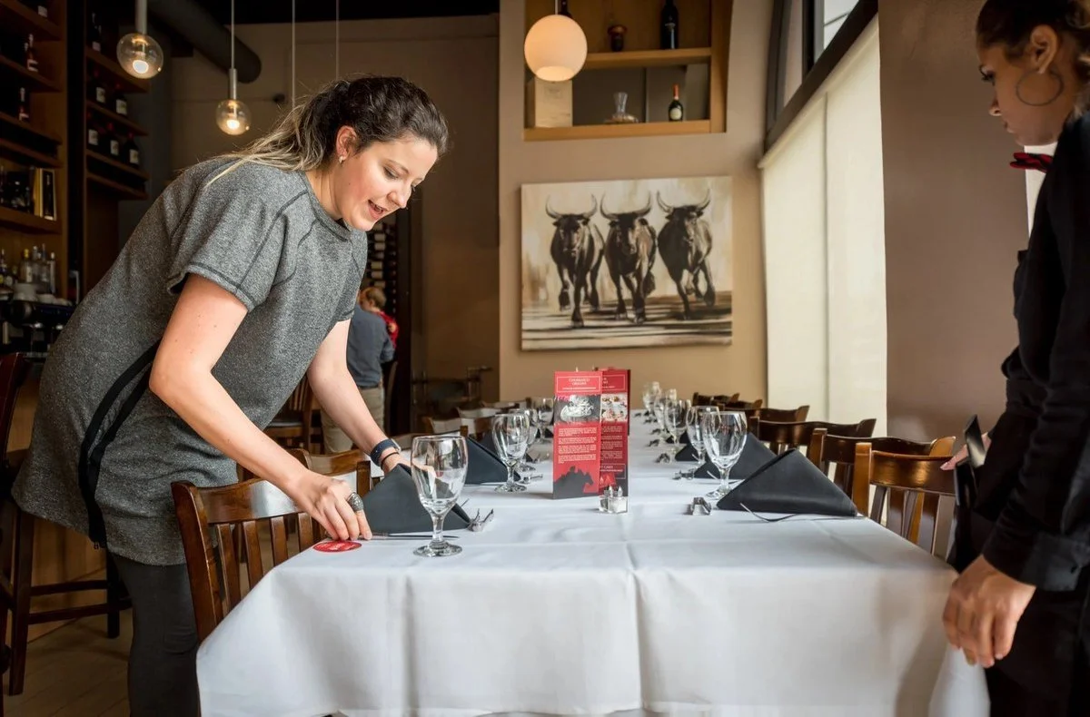 Server setting a long dining table before service