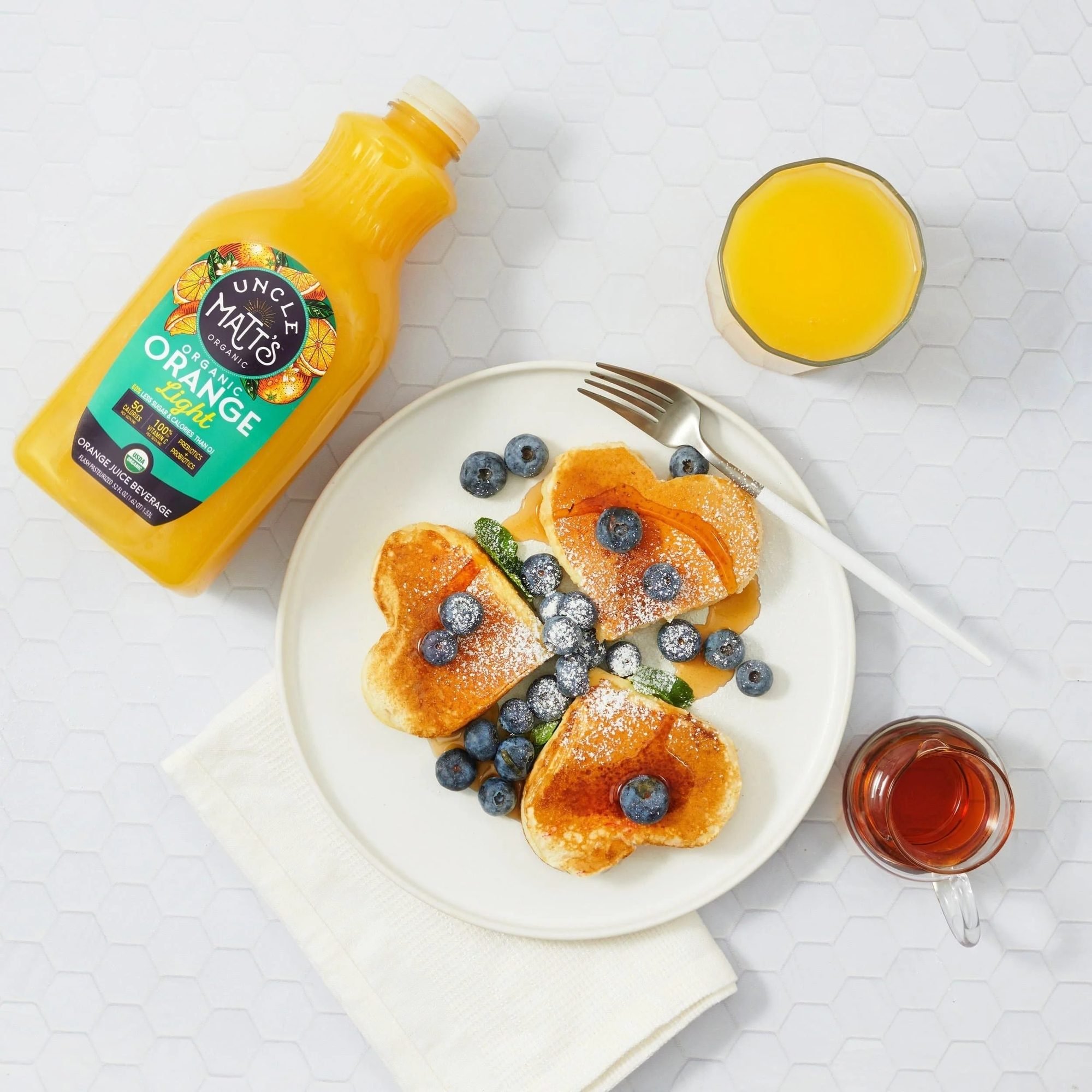 Uncle Matt's organic orange juice with pancakes and blueberries at breakfast, CPG beverage photography