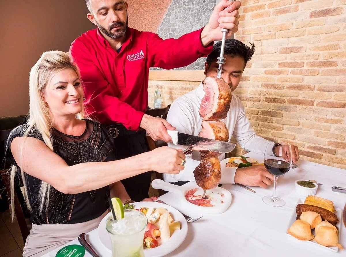 Server carving meat tableside for diners