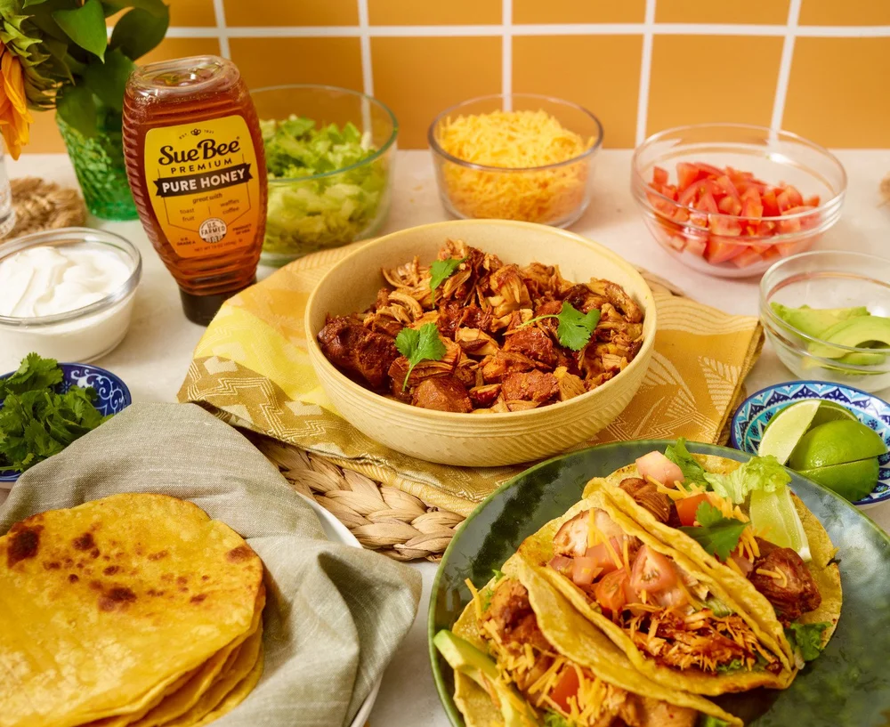 Family taco bar spread with tortillas and toppings on blue tile. Lifestyle food photography for Mexican food and grocery brands.