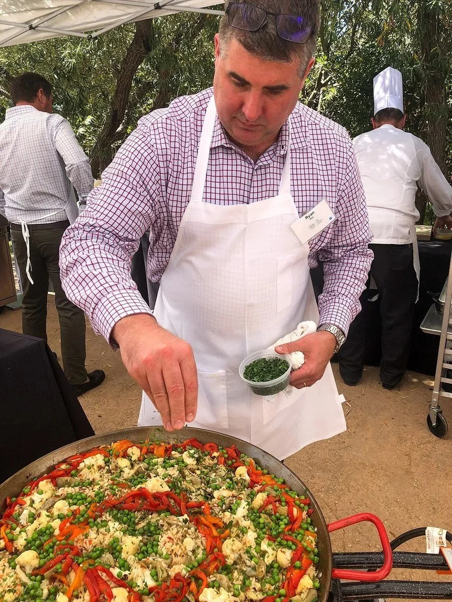 Chef cooking a large pan of paella at an outdoor event